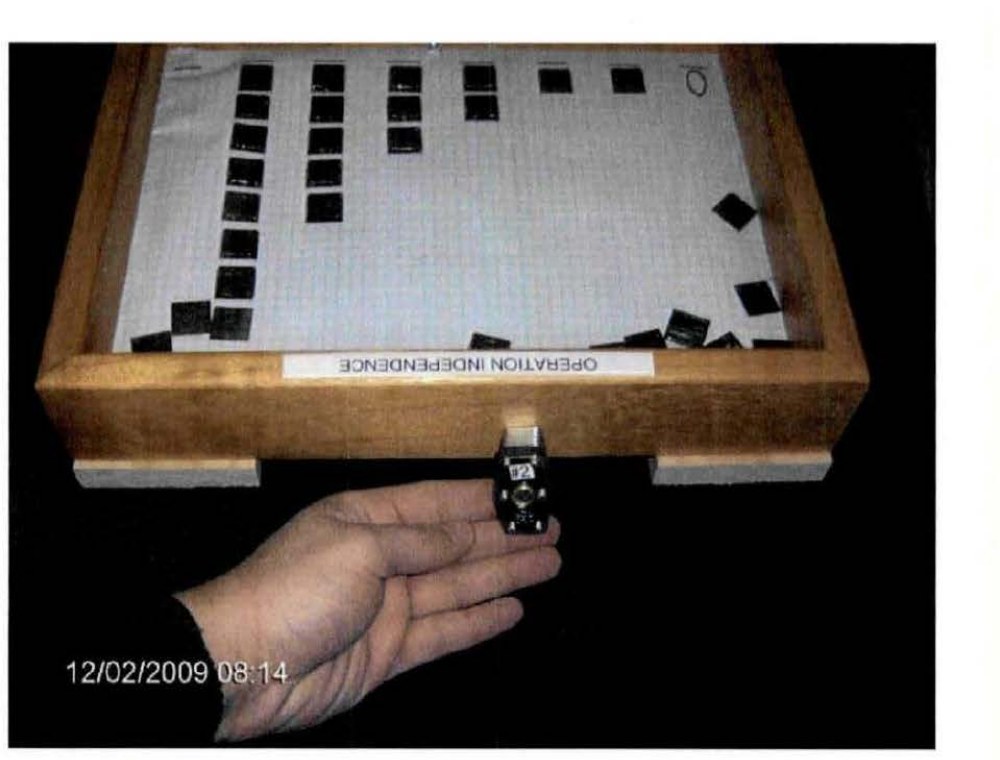 DOW-UAP-D173: one of the padlocked wooden "Fibonacci boxes" for the Utah ranch, labelled "OPERATION INDEPENDENCE", time-stamped 12/02/2009 08:14. Dark tiles glued to graph paper form a Fibonacci series; loose tiles inside are for any intelligence to assemble the next number.